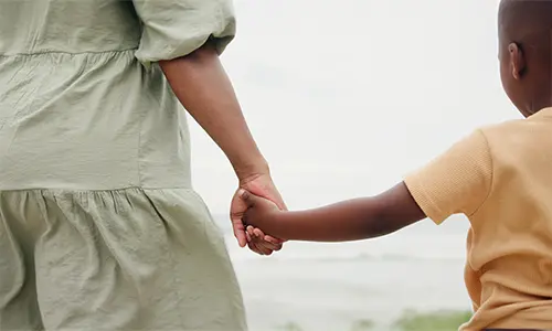 Aboriginal woman holding child hand from behind
